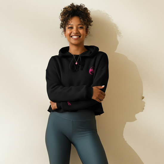 Woman wearing a black hoodie and teal shorts against a beige background